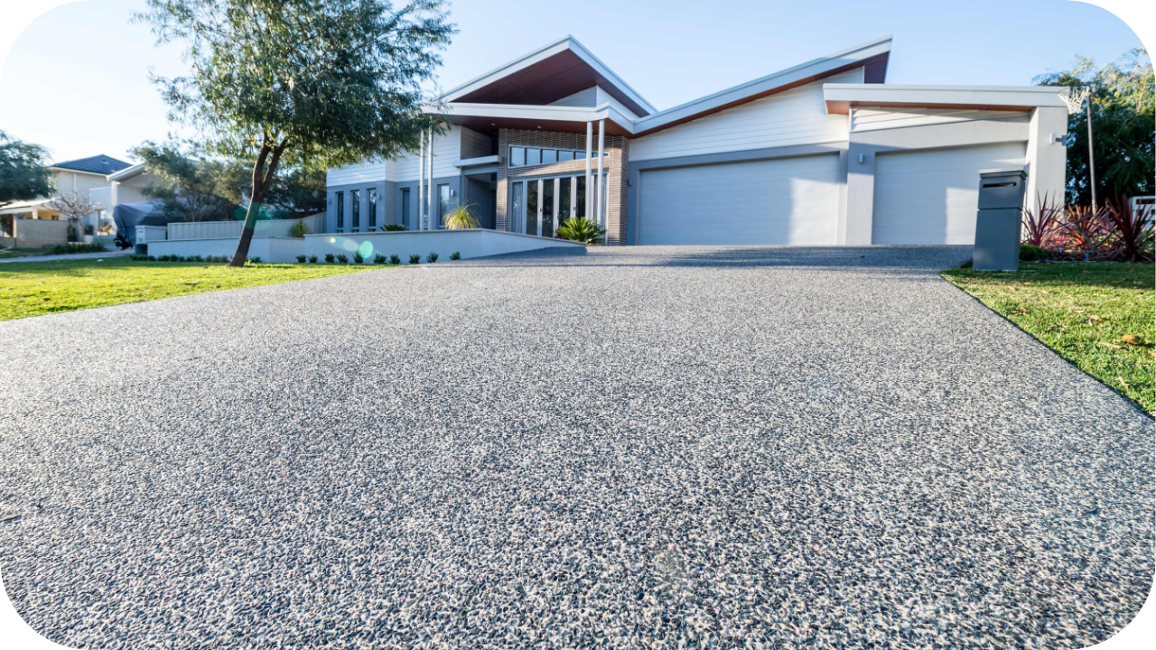 Modern residential home with a wide, freshly finished exposed aggregate concrete driveway leading to the front garage and entryway.