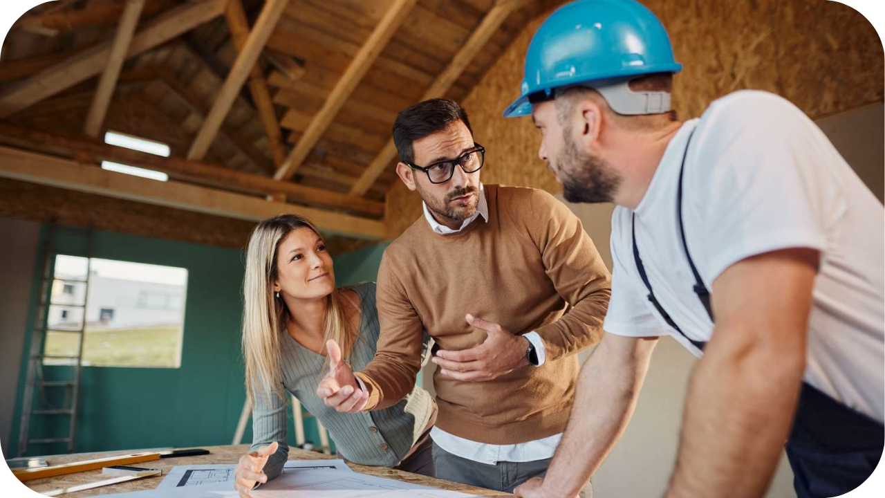 Couple consulting a Melbourne concrete contractor inside a partially built home, reviewing project plans and discussing service options.
