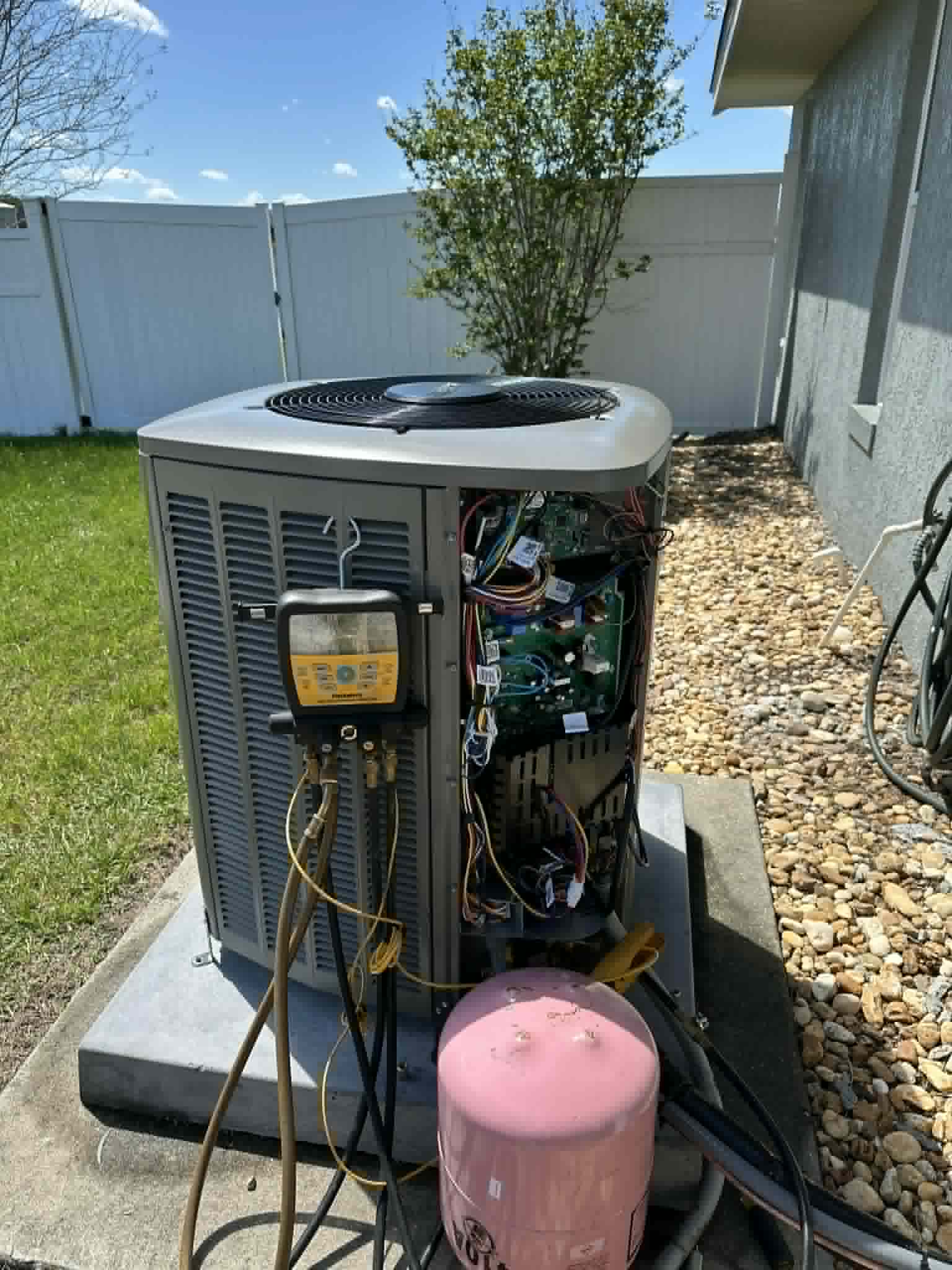 Outdoor AC unit with the service panel open and test instruments connected during a performance check