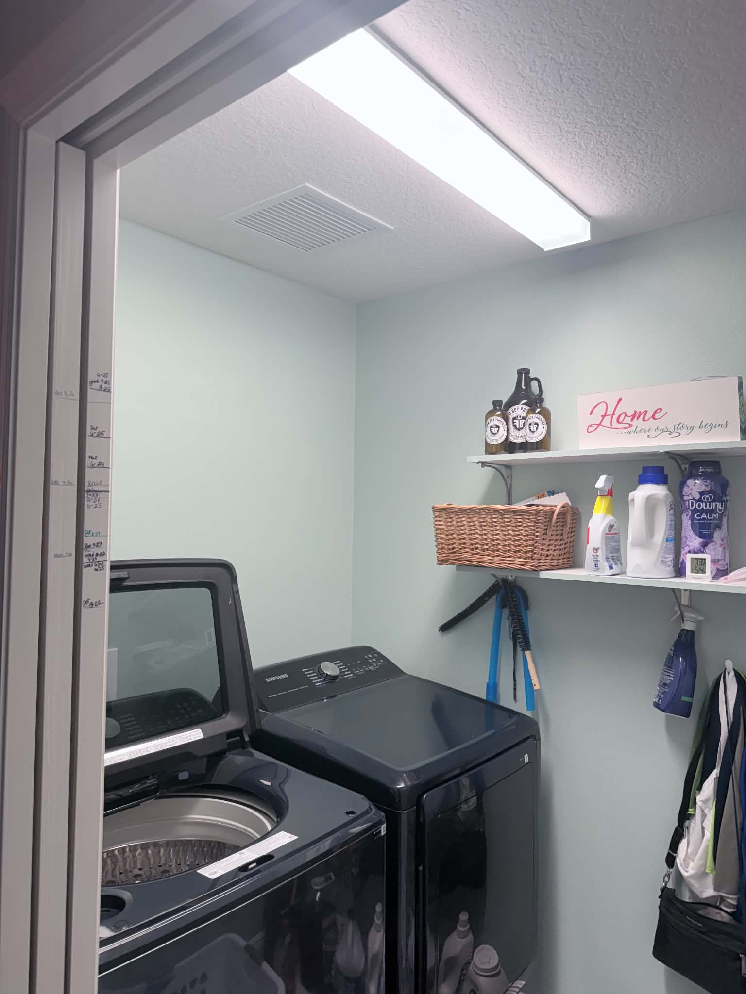 AC return grille installed in the ceiling of a laundry room directly above the washer and dryer, pulling lint into the unit