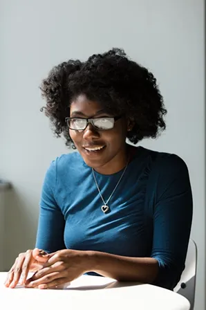 Smiling professional in blue shirt and glasses sitting at desk