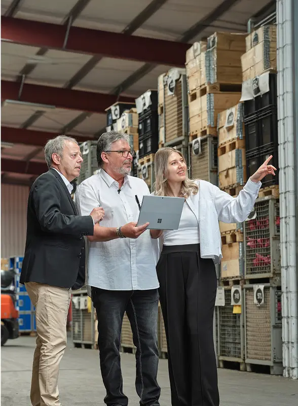konstante Transport Otimierung - Drei Mitarbeiter stehen mit Laptop im Lager und besprechen sich.