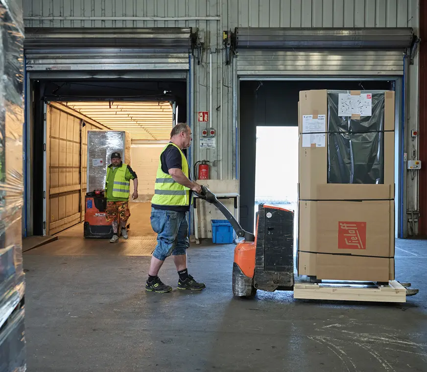 kompetenter Stückguttransport bei Pohl - Zwei Mitarbeiter verladen Ware mit dem Hubwagen.