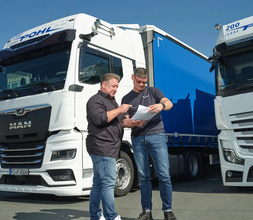 sichere Teil und Komplettladungen bei Pohl - Zwei Pohl-Mitarbeiter besprechen vor den LKWs einen Fahrtenplan.