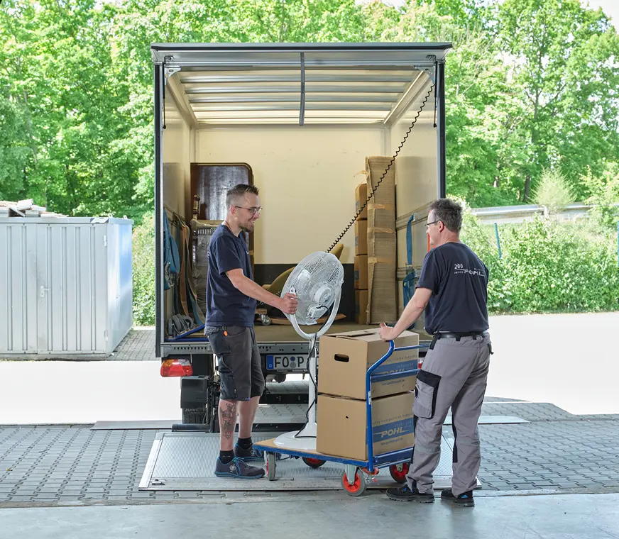 Privater Umzug bei Pohl - zwei freundliche Mitarbeiter befördern Möbel in einen Umzugswagen