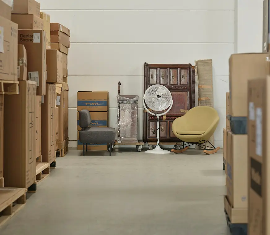 Einlagerungen ei Pohl - ein Ventilator, Sessel, Kommode und Kartons in einer Garage