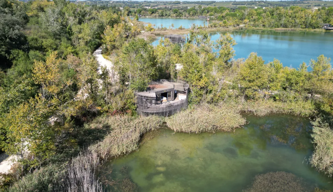 Aerial view of a wetland with multiple lakes and a small, round wooden observation deck surrounded by trees.
