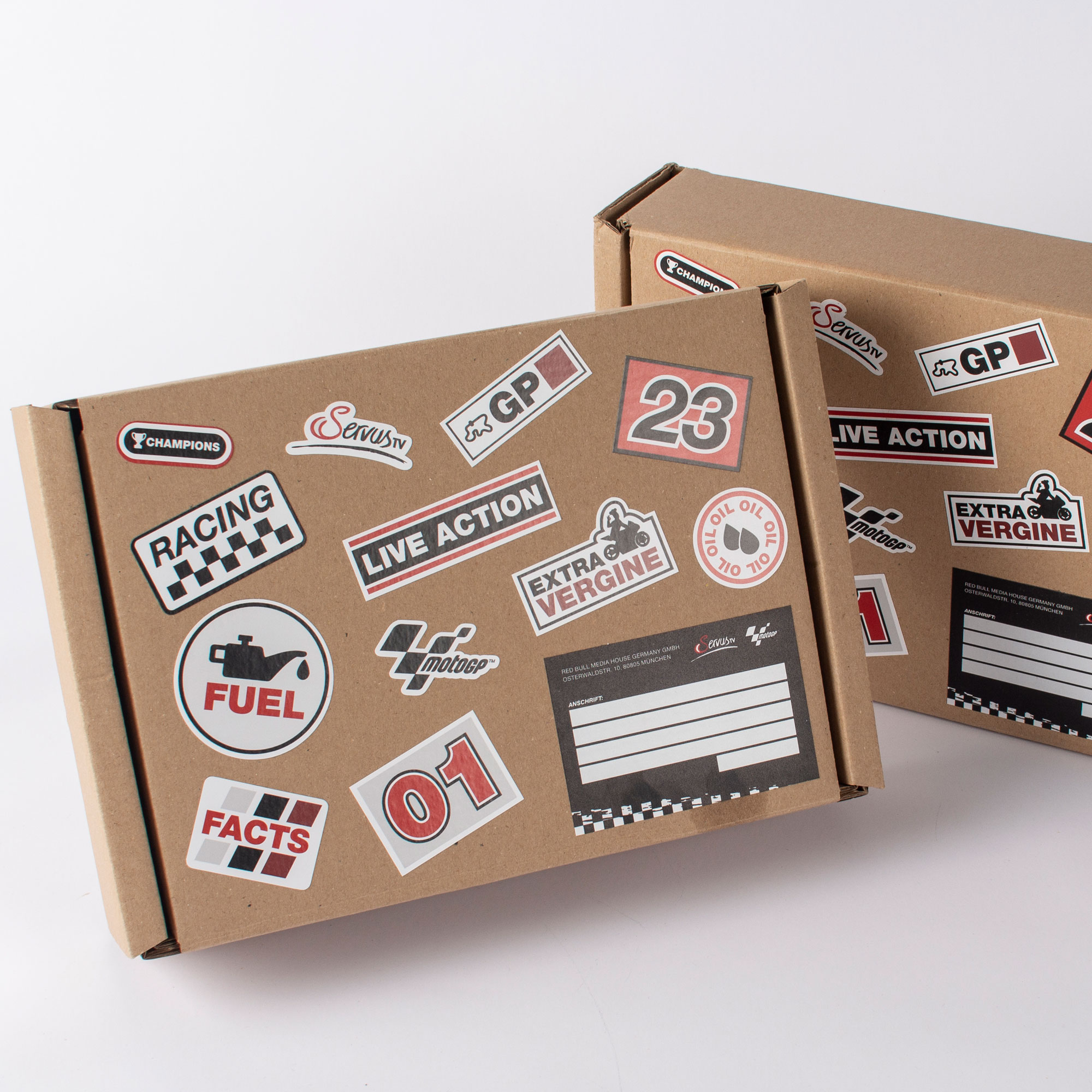 Versandkarton im MotoGP-Look, verziert mit Rennsport-Stickern und ServusTV-Branding