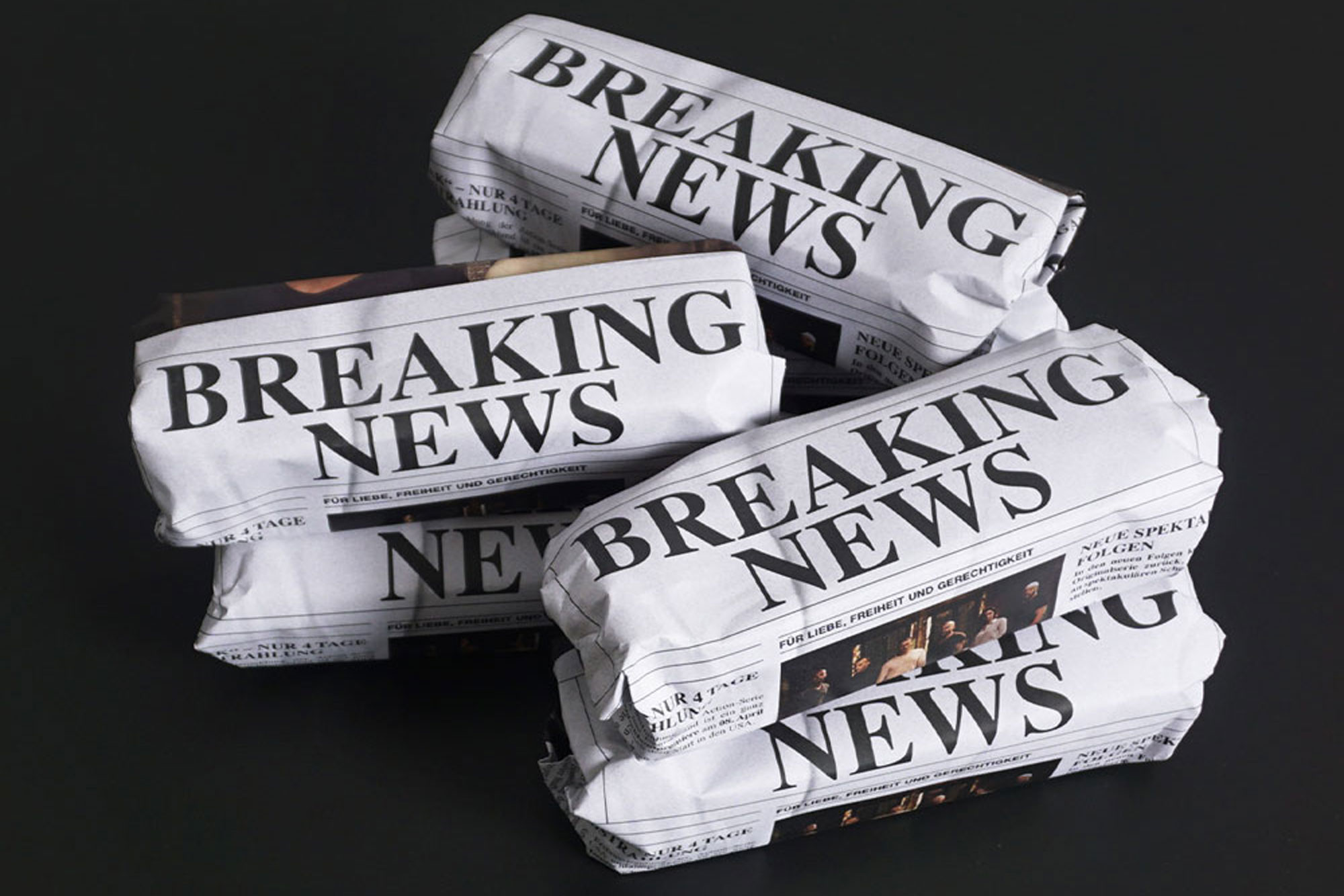 Mehrere Zeitungspapiere als Quader geformt übereinander liegend, mit der Aufschrift "Breaking News".