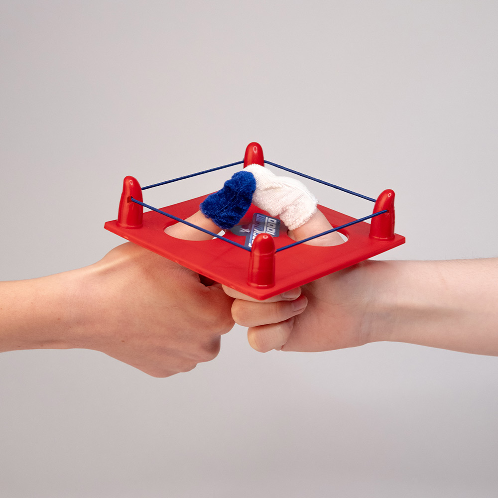 Zwei Hände im Daumenwrestling-Ring mit Mini-Handschuhen – das kreative Gimmick der WWE-Werbebox zum SmackDown-Jubiläum.