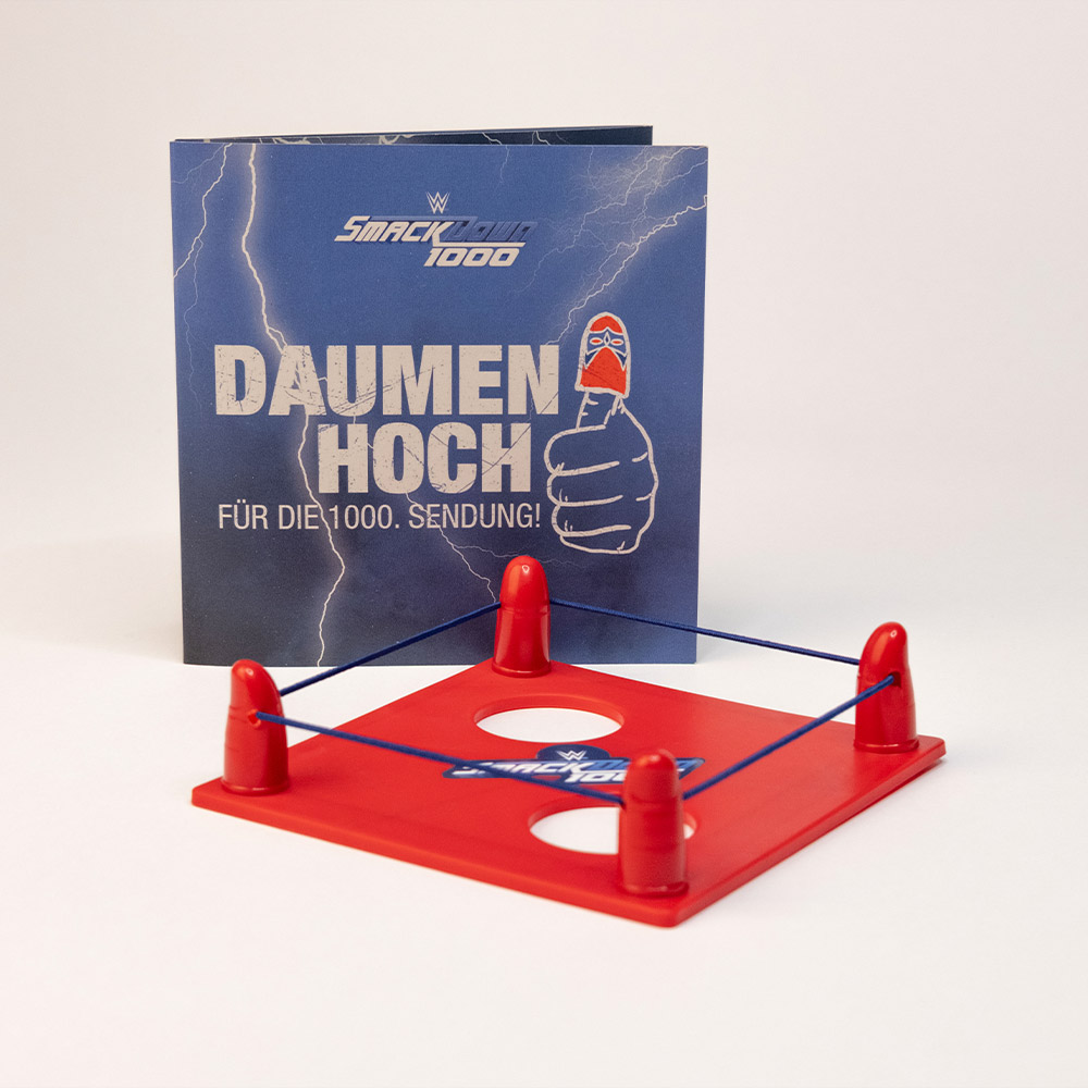 Mini-Daumenring und Karte mit „Daumen hoch“-Claim – das zentrale Giveaway der Werbebox zum 1000. SmackDown-Event.

