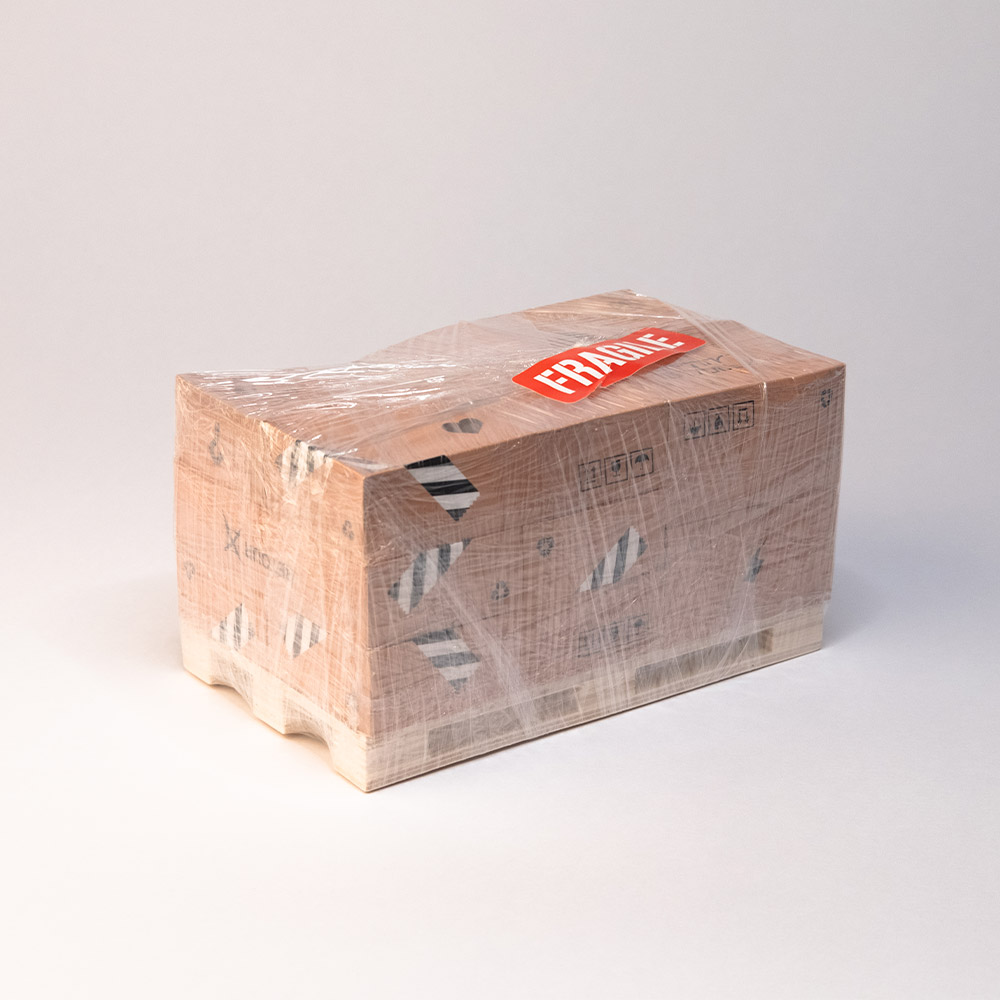 Miniatur-Palette in Folie mit „Fragile“-Sticker – auffällige Versandaktion.