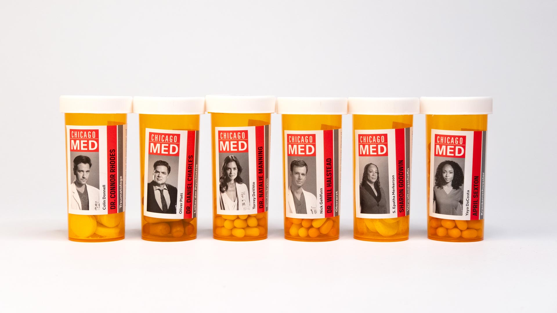Pillendosen mit Etiketten mit Gesichter drauf von Serie Chicago Med. 