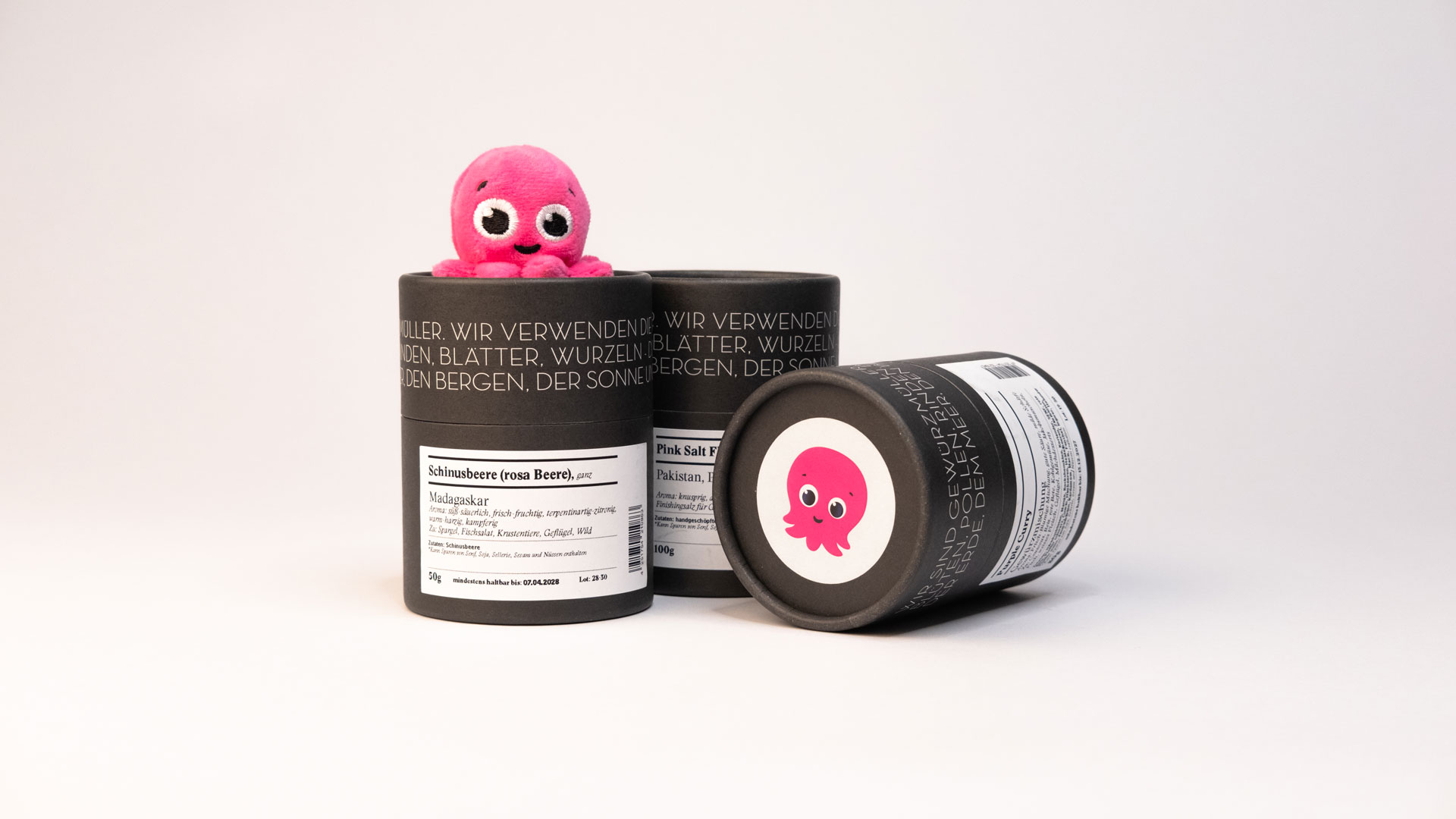 Gewürze arrangiert, zwei Dosen stehen nebeneinander, 1 liegt. Aufkleber mit pinknem Octopus sichtbar.
