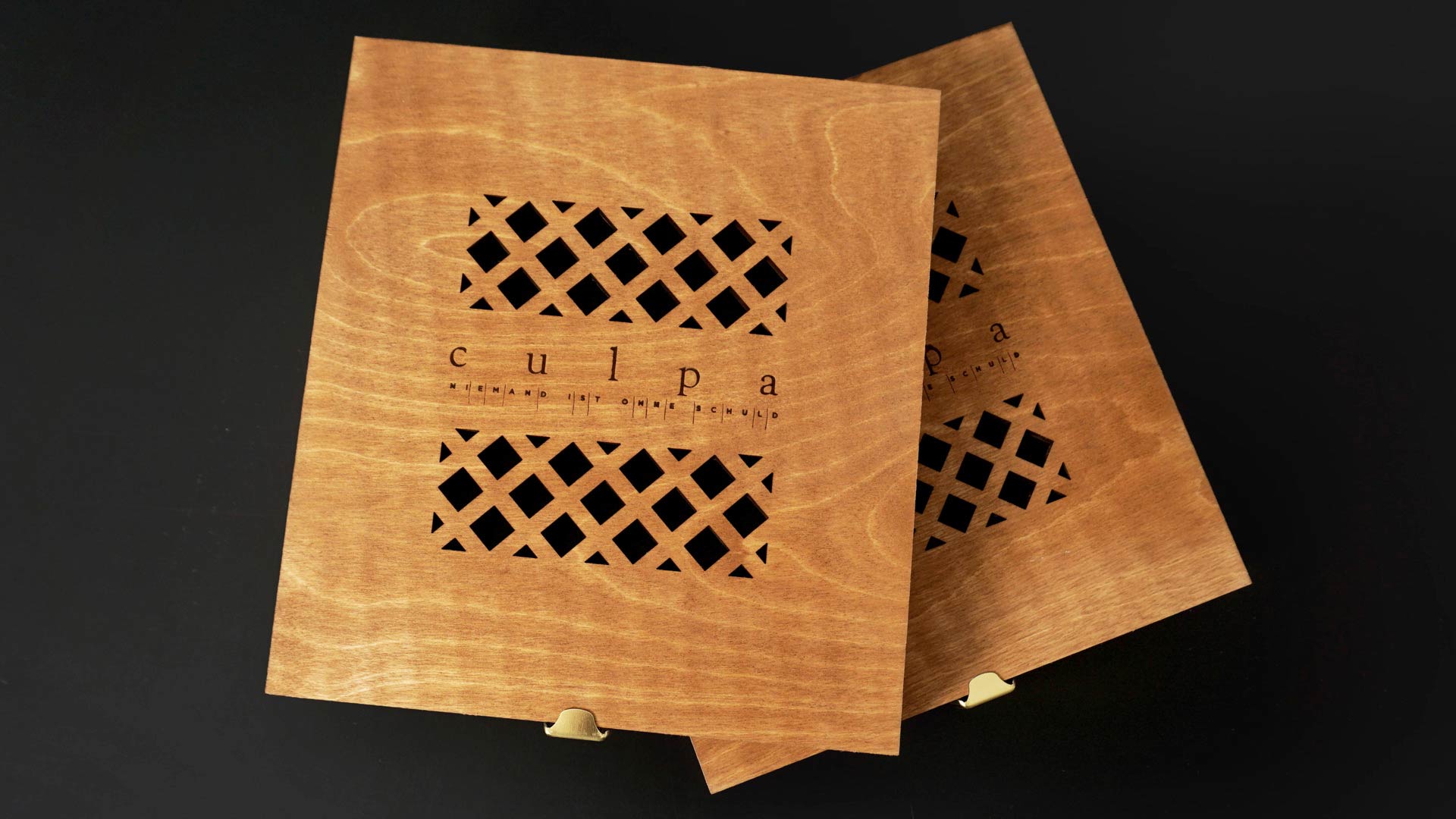 Geschlossene Holzbox  mit dem Titel „culpa – Niemand ist ohne Schuld“ und einem aufwendig eingravierten Gittermuster.