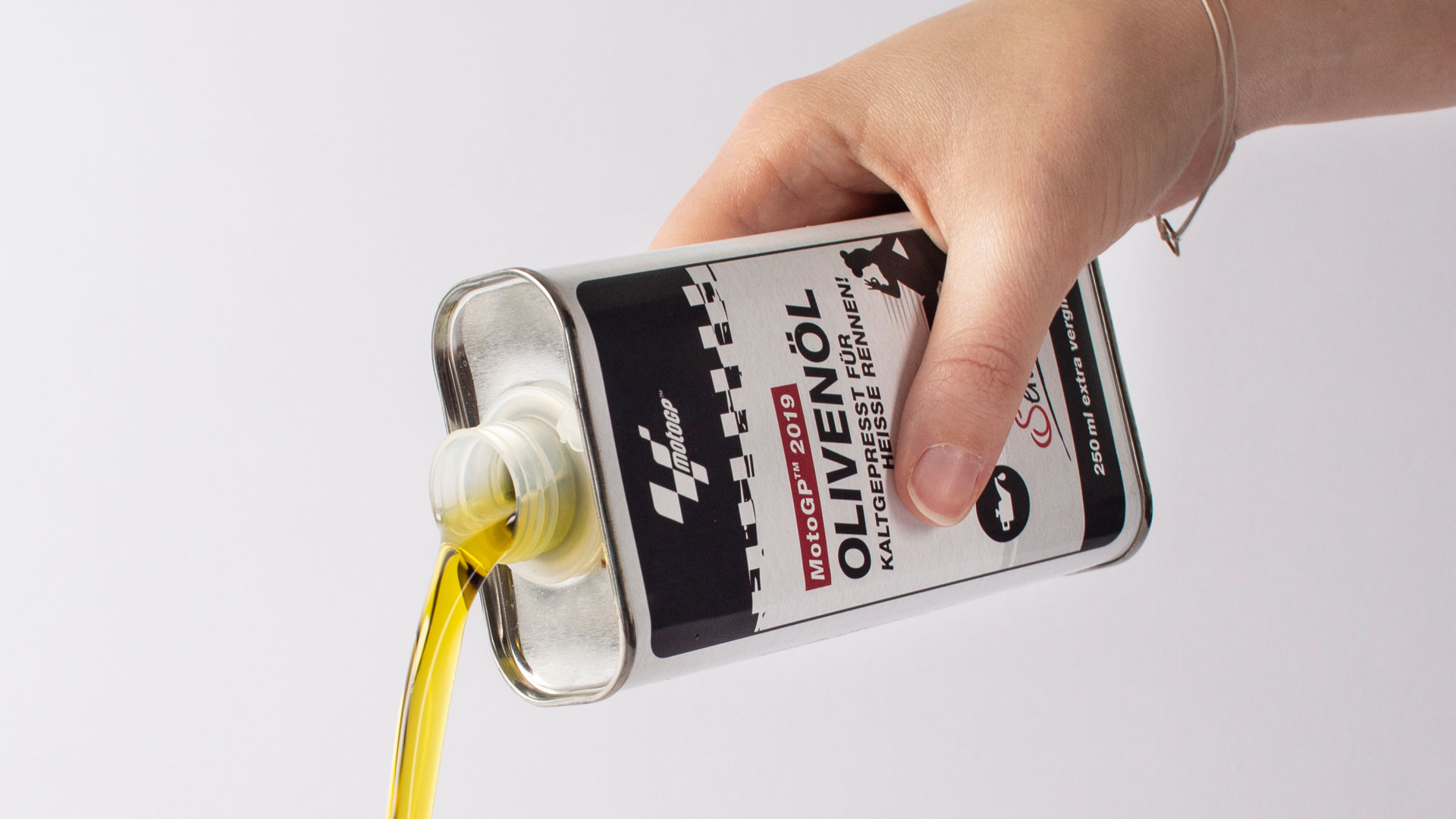 Olivenölflasche im Design einer Motoröl-Dose wird ausgegossen.