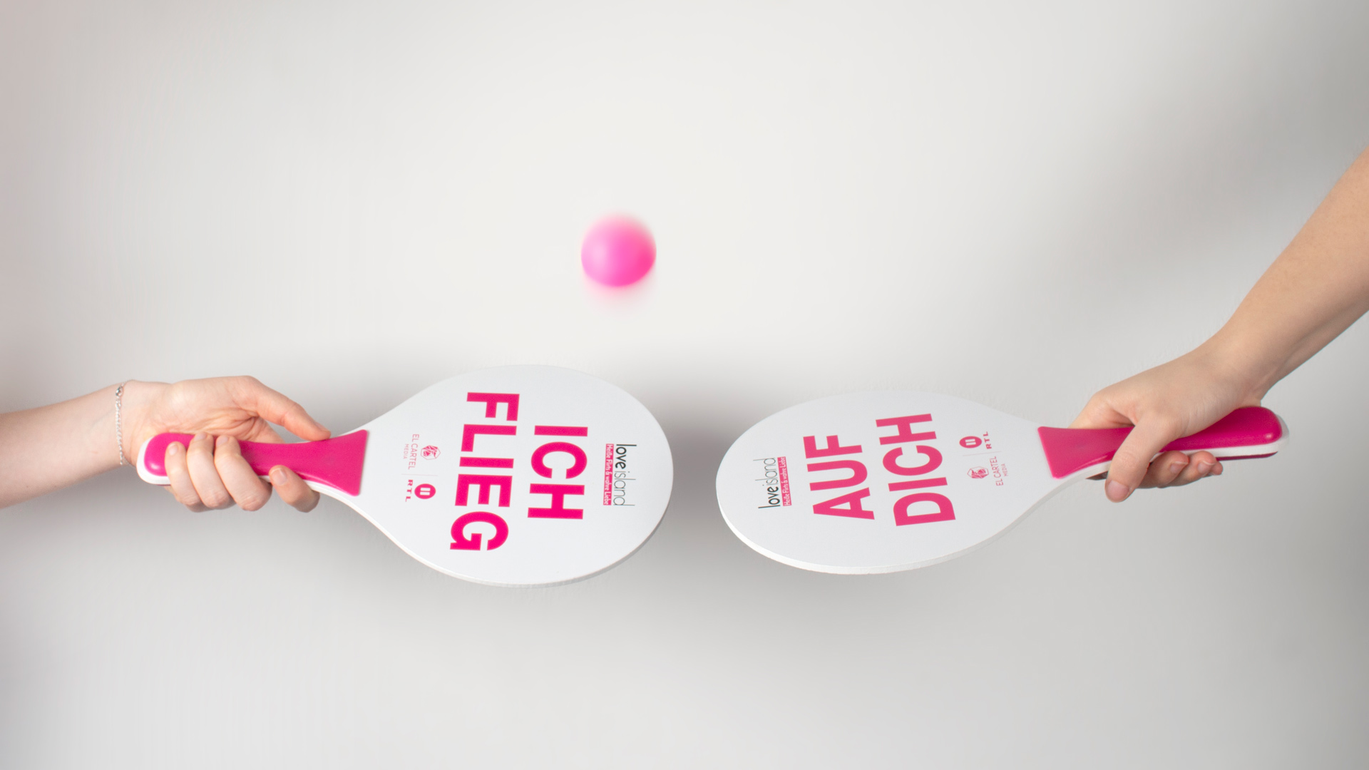 Zwei pink-weiße Beachball-Schläger mit Slogans „Ich flieg“ und „auf dich“ aus Love Island Promo. Zum Staffel Start.