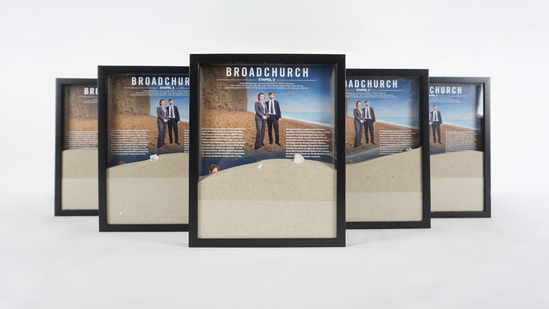 Gerahmte Bilder mit Sand im schwarzen Bilderahmen zur Serie Broadchurch – visuell an den Serieninhalt Mord am strand angepasst.