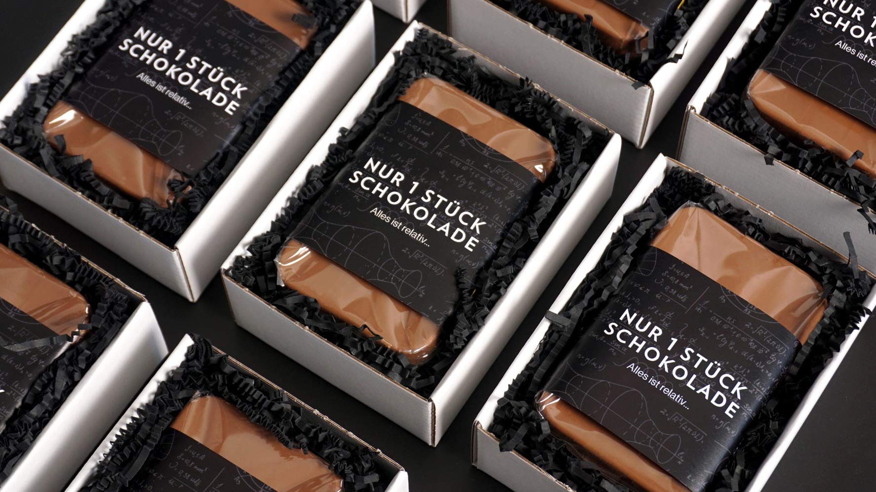Schokoladenbars in mehreren Reihen liegend, mit Aufschrift "nur 1 Stück Schokolade".