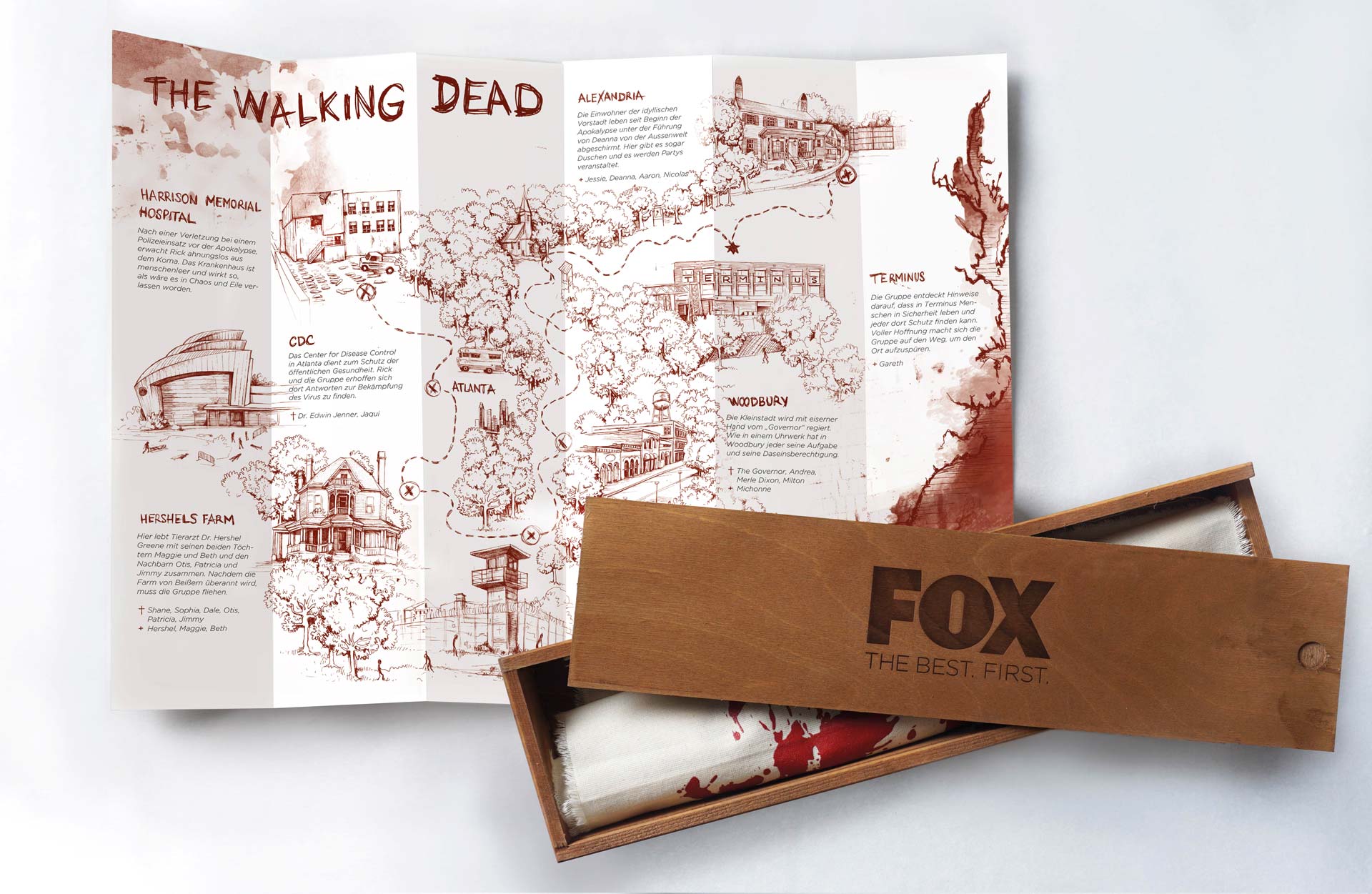Aufgefalteter Leporello mit handgezeichneter Karte zur Welt von „The Walking Dead“, daneben die geöffnete FOX-Holzbox mit Geschirrtuch.