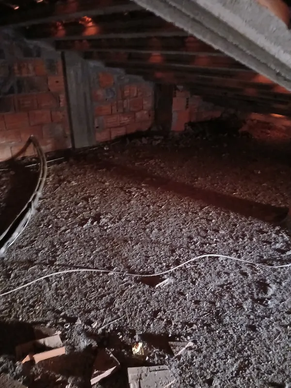 Chão de um sótão antes do isolamento, com pó e restos de obra