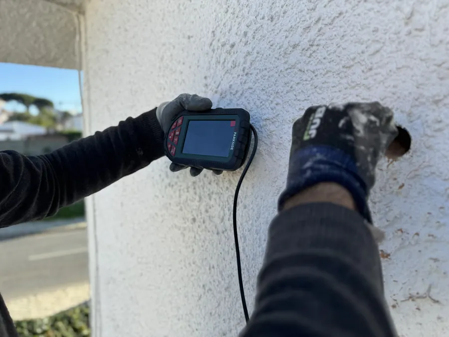EnergyEase installer checking inside a wall with the inspection camera, through a small hole