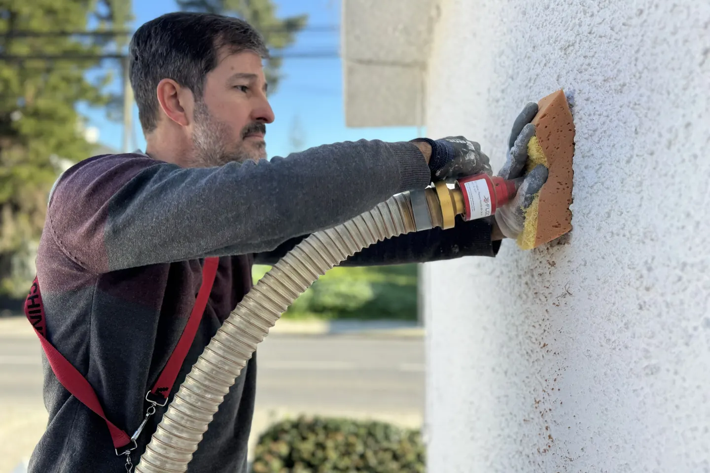 EnergyEase installer blowing mineral wool into the cavity of a wall through a small hole in the façade