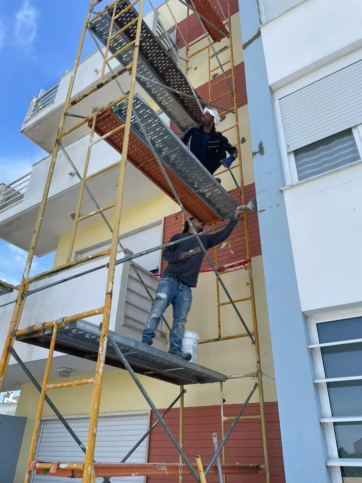 Two workers closing the holes in the façade with mortar