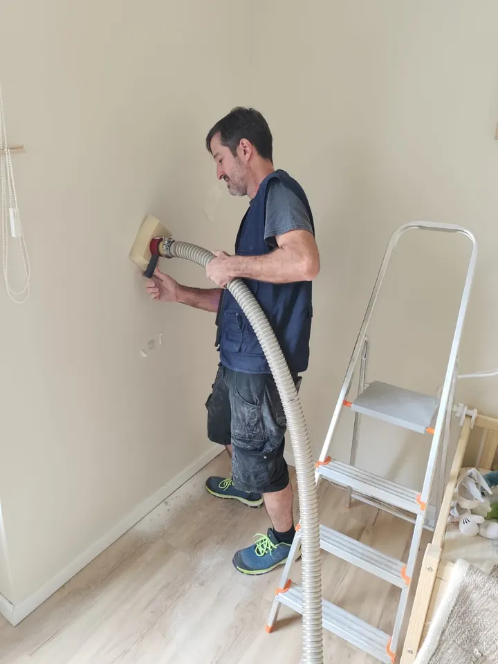 Installer blowing mineral wool into a wall from inside the house