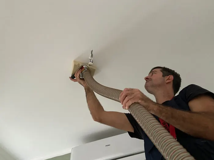 Técnico da EnergyEase a insuflar lã mineral por um ponto de luz do teto