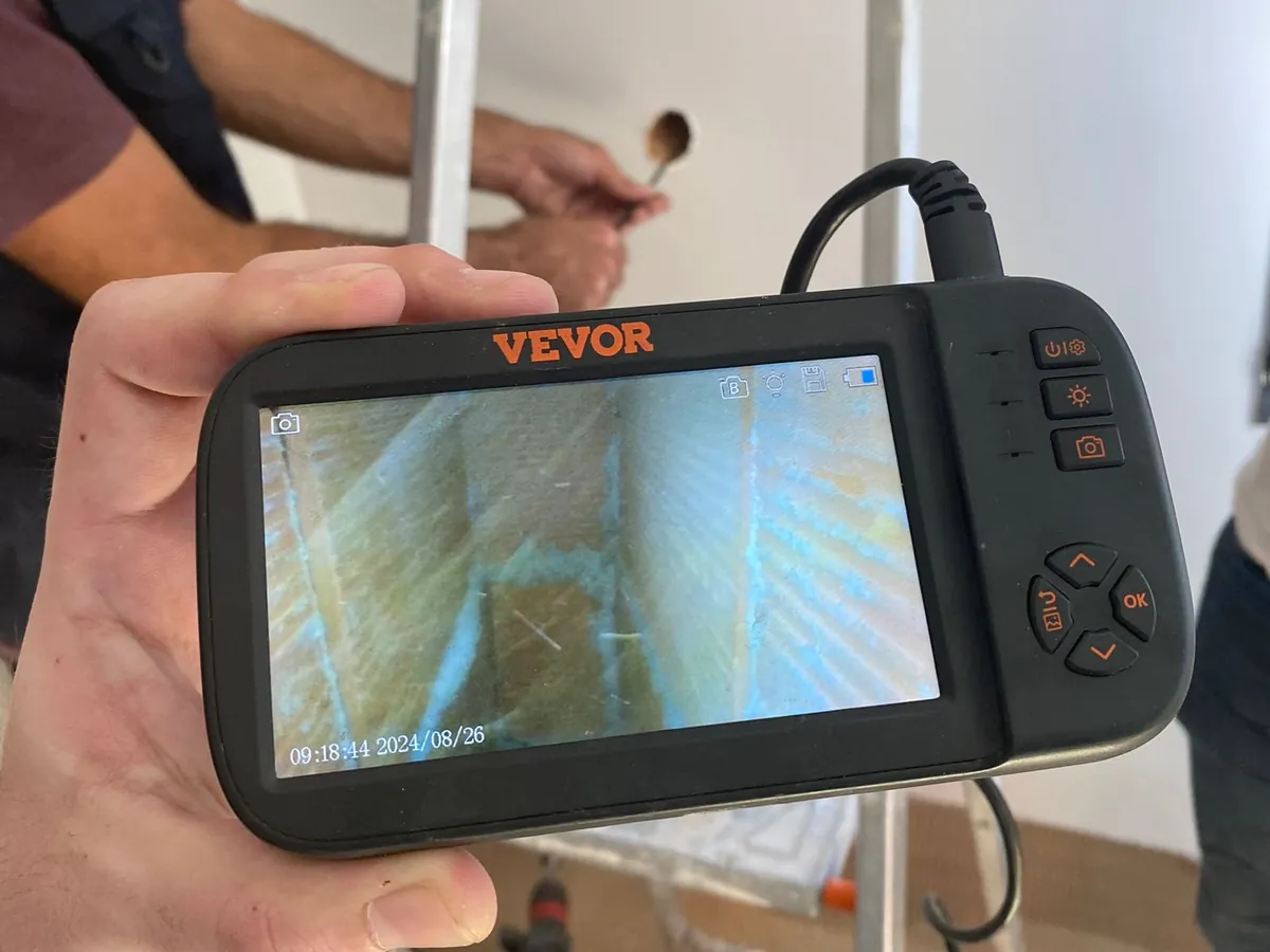 Ecrã da câmara de inspeção com a imagem do interior de uma caixa de ar, com o furo na parede ao fundo