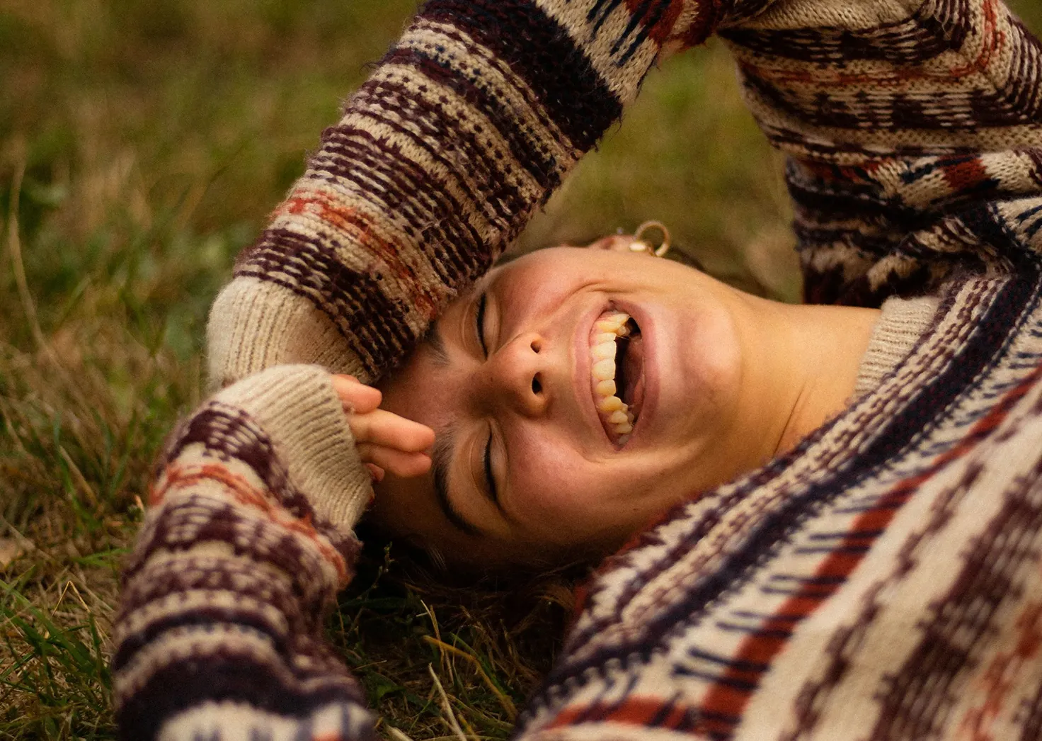 woman laughing on grass, happy after psychedelic ceremony