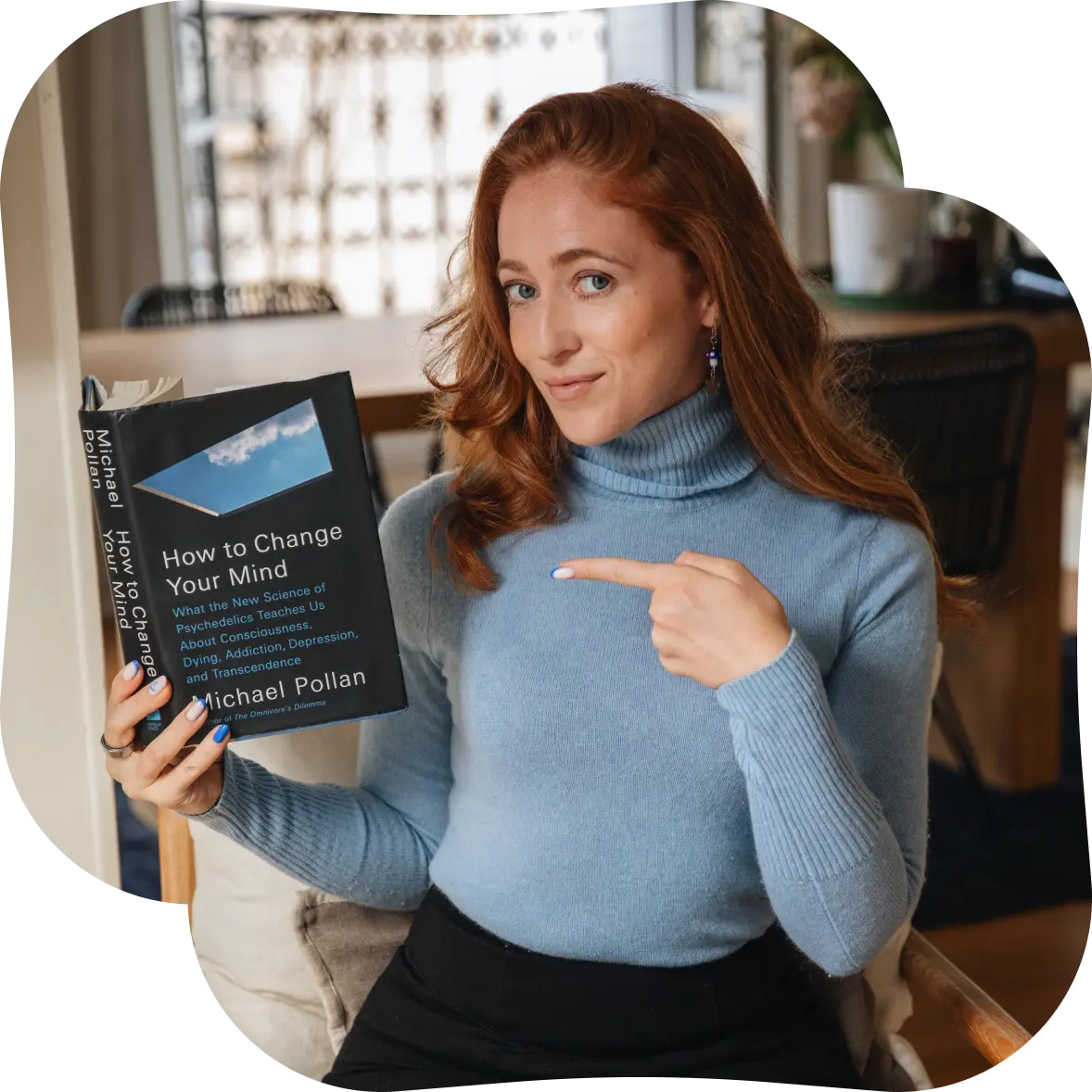Psychedelic coach & guide based in lisbon and paris meredith detko pointing to book How to change your mind by Michael Pollan. 
