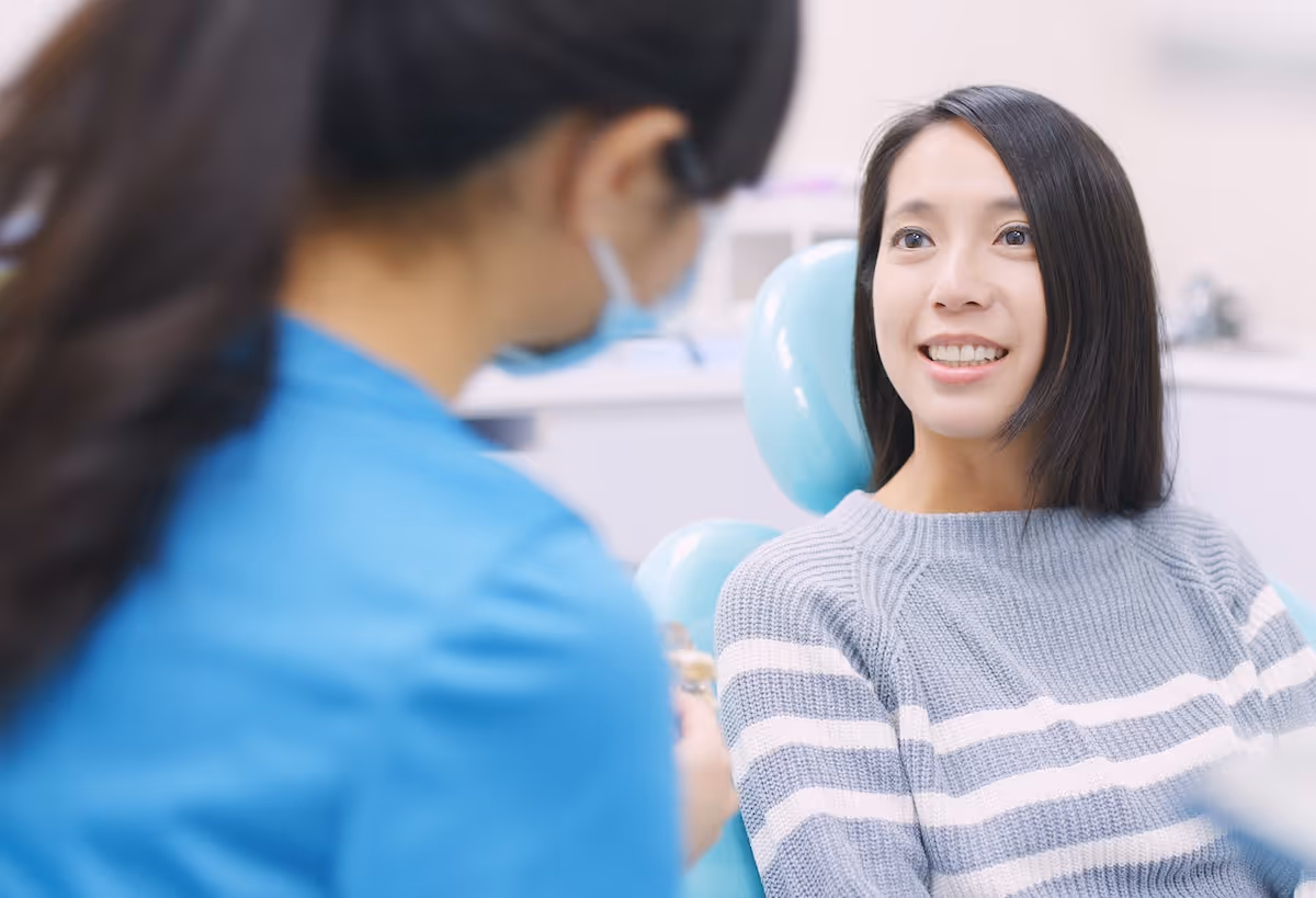 A woman sitting in a dentist chair with a smile on her face.