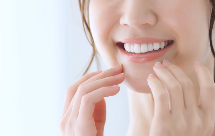 A woman is smiling and holding her hand near her face.