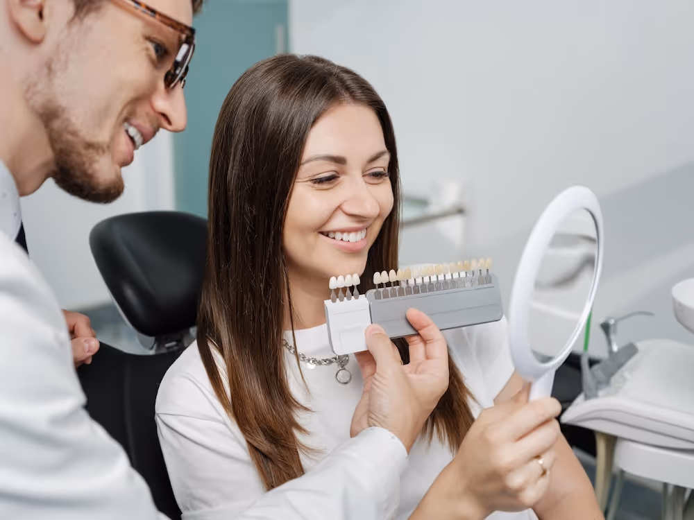A woman sitting in a dentist chair looking in a mirror.