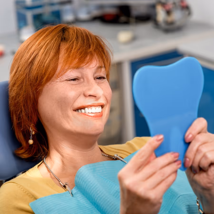 A woman with red hair holding a blue mirror.