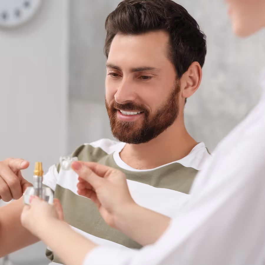 A dentist with an educational model of dental implant consulting a patient in clinic