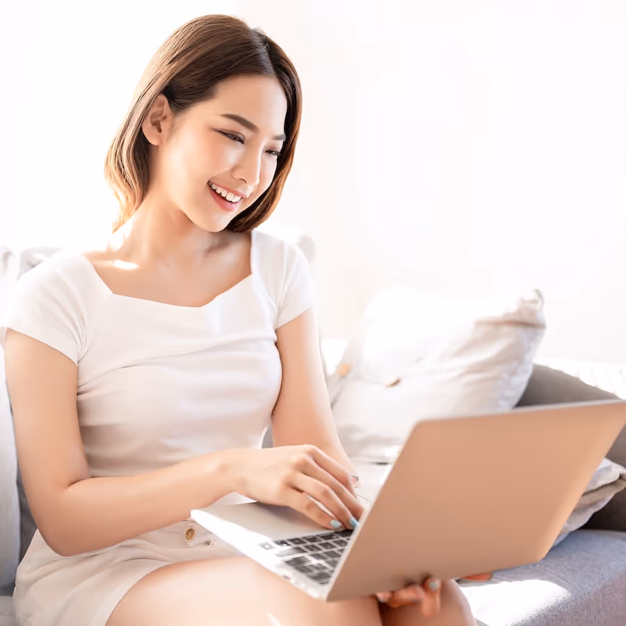 A woman sitting on a couch using a laptop computer.