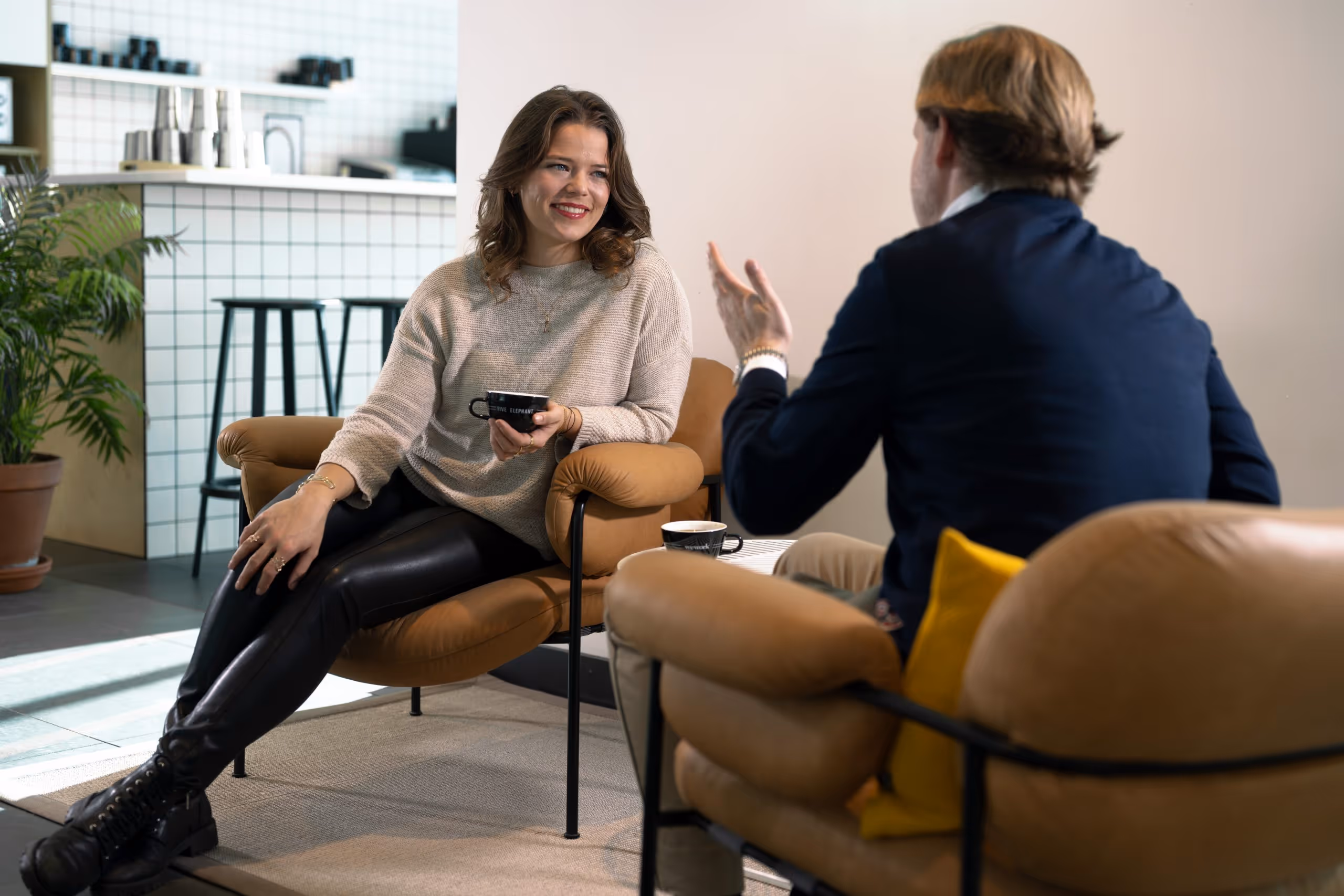 Zwei Personen sitzen in einem modernen Café und unterhalten sich, während sie Kaffee trinken.