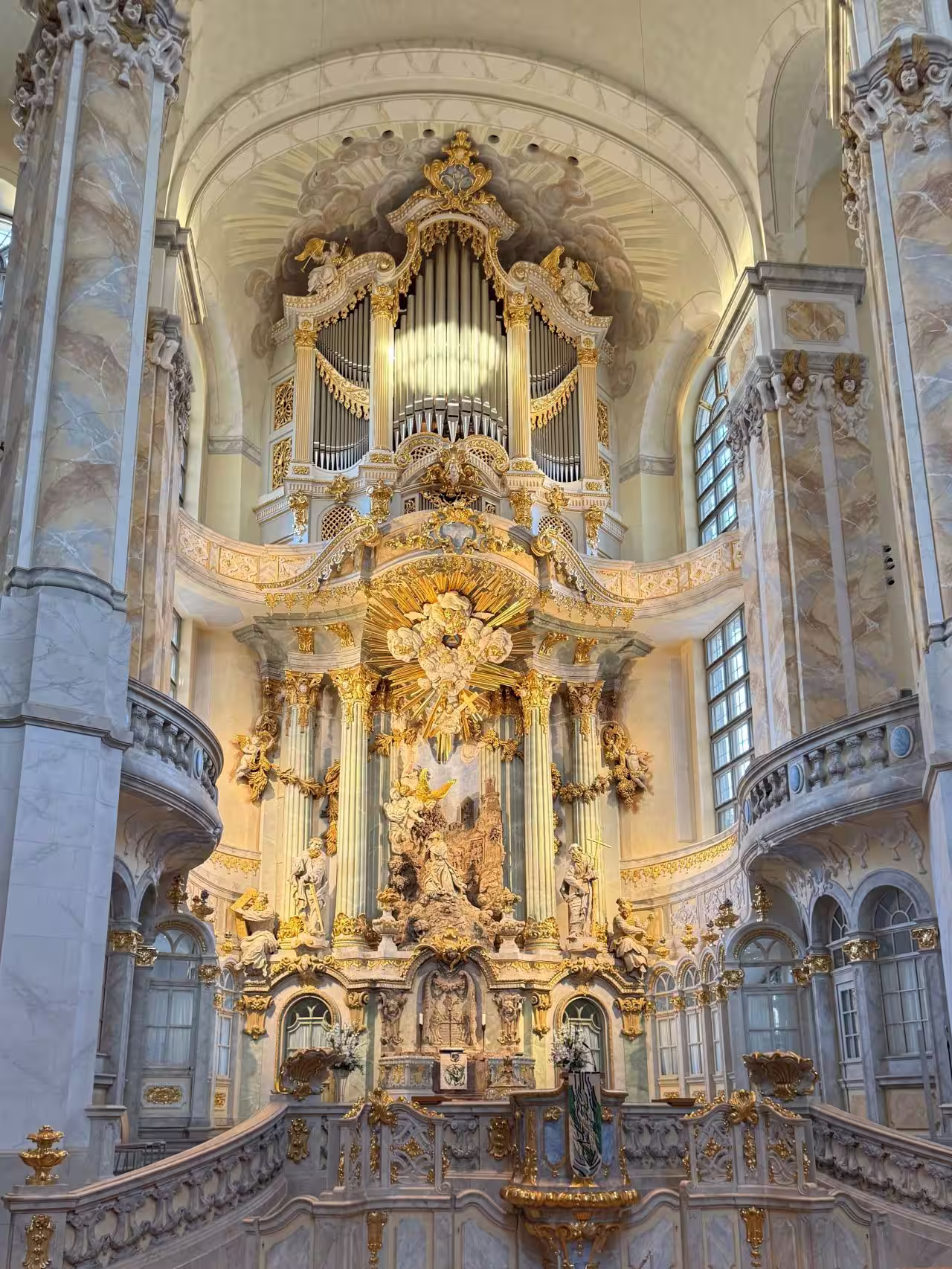 Prächtig verzierte Barockorgel mit goldenen Details in einer Kirche mit hohen Säulen und großen Fenstern.