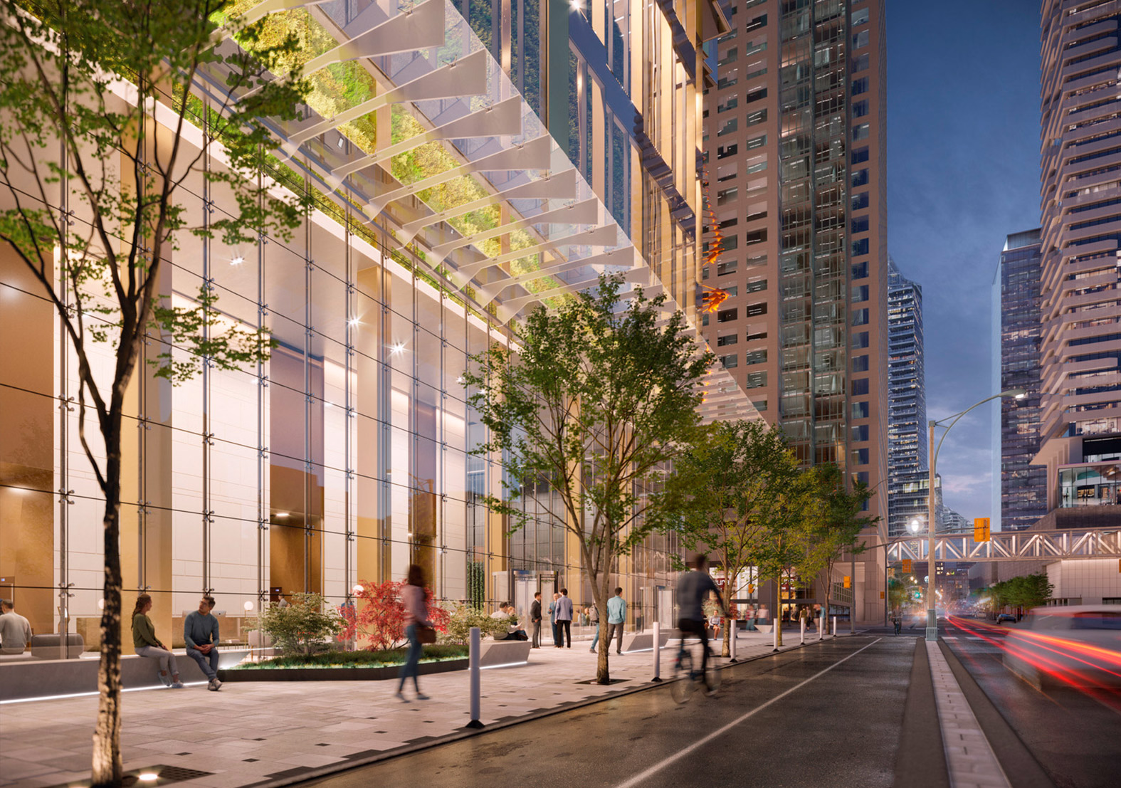 Nighttime street-level view of 11 Bay with tall illuminated glazing and landscaping along the sidewalk.