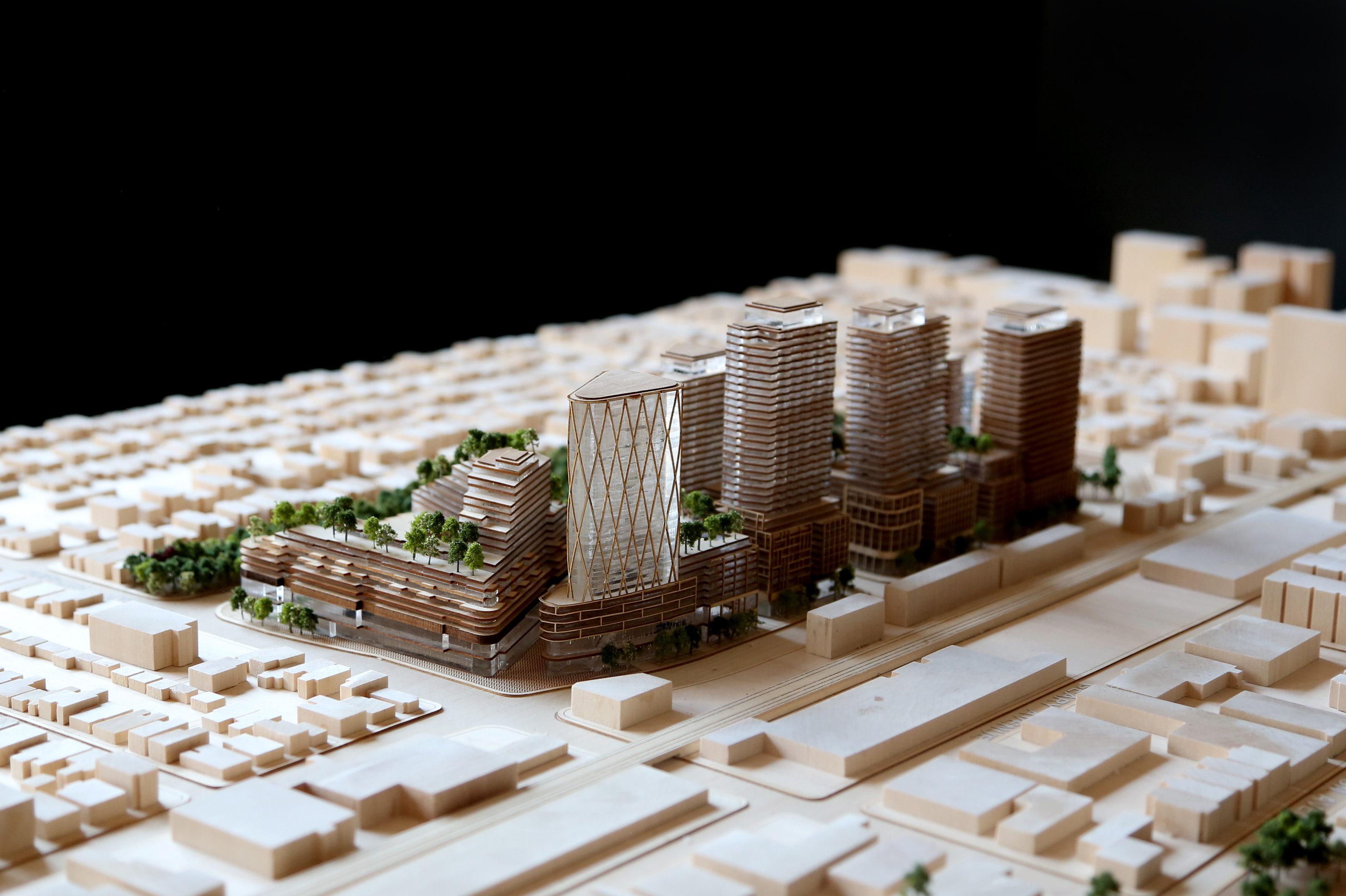 Architectural scale wooden model of Galleria Mall, an urban development featuring multiple modern high-rise buildings with greenery on rooftops, set among a grid of smaller structures.