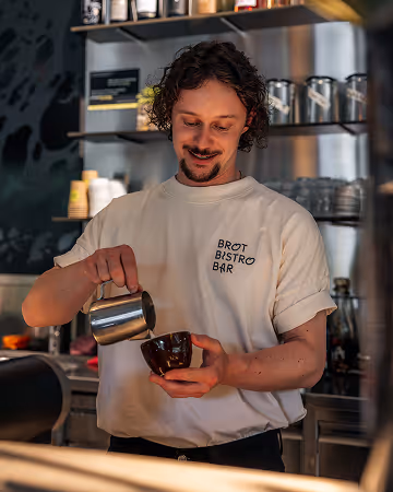 Barista giesst Milchschaum für einen Kafi im Brot Bistro Bar Zürich – hausgemachter Kaffee