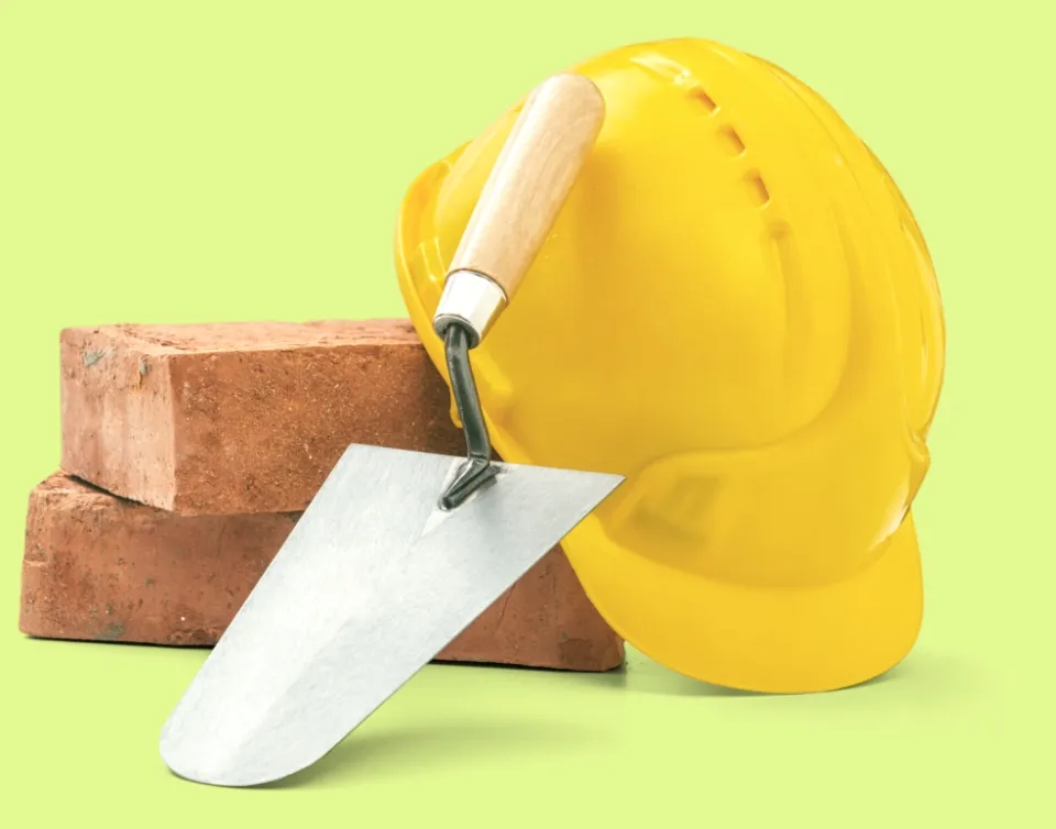 Bricks, a mason's trowel and a yellow hard hat