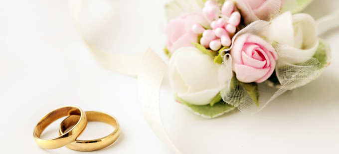 bagues de mariage sur une table blanche à côte fleurs