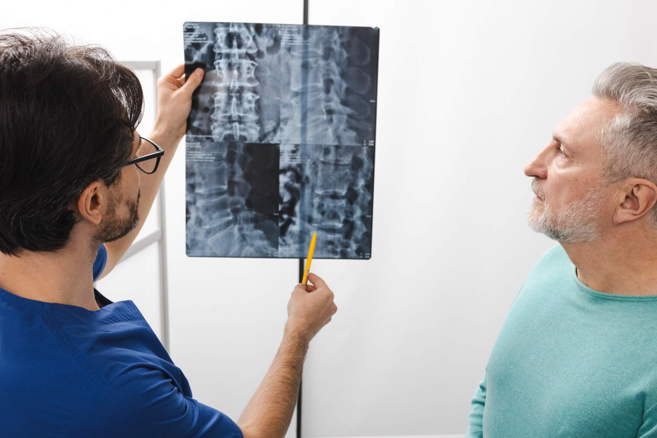 Doctor reviews a spinal X-ray with a patient while explaining different SCI levels.