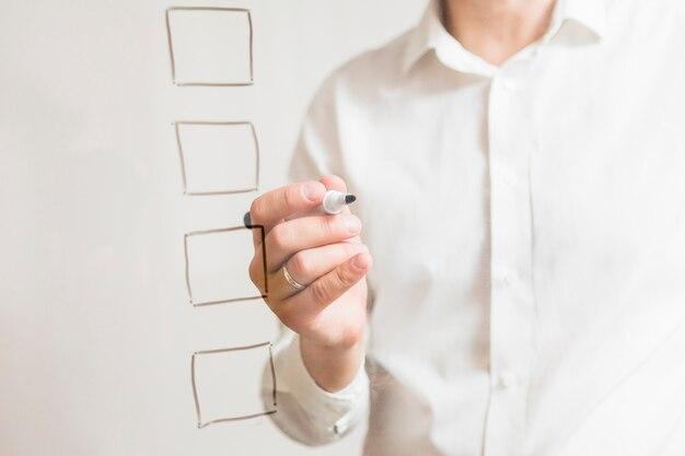 Free photo check boxes on transparent glass board in front of businessperson holding marker