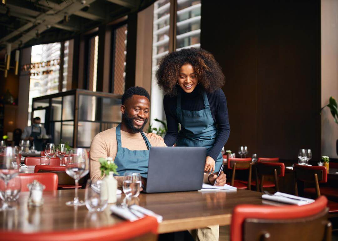 Deux propriétaires d'un restaurant regardent un ordinateur.