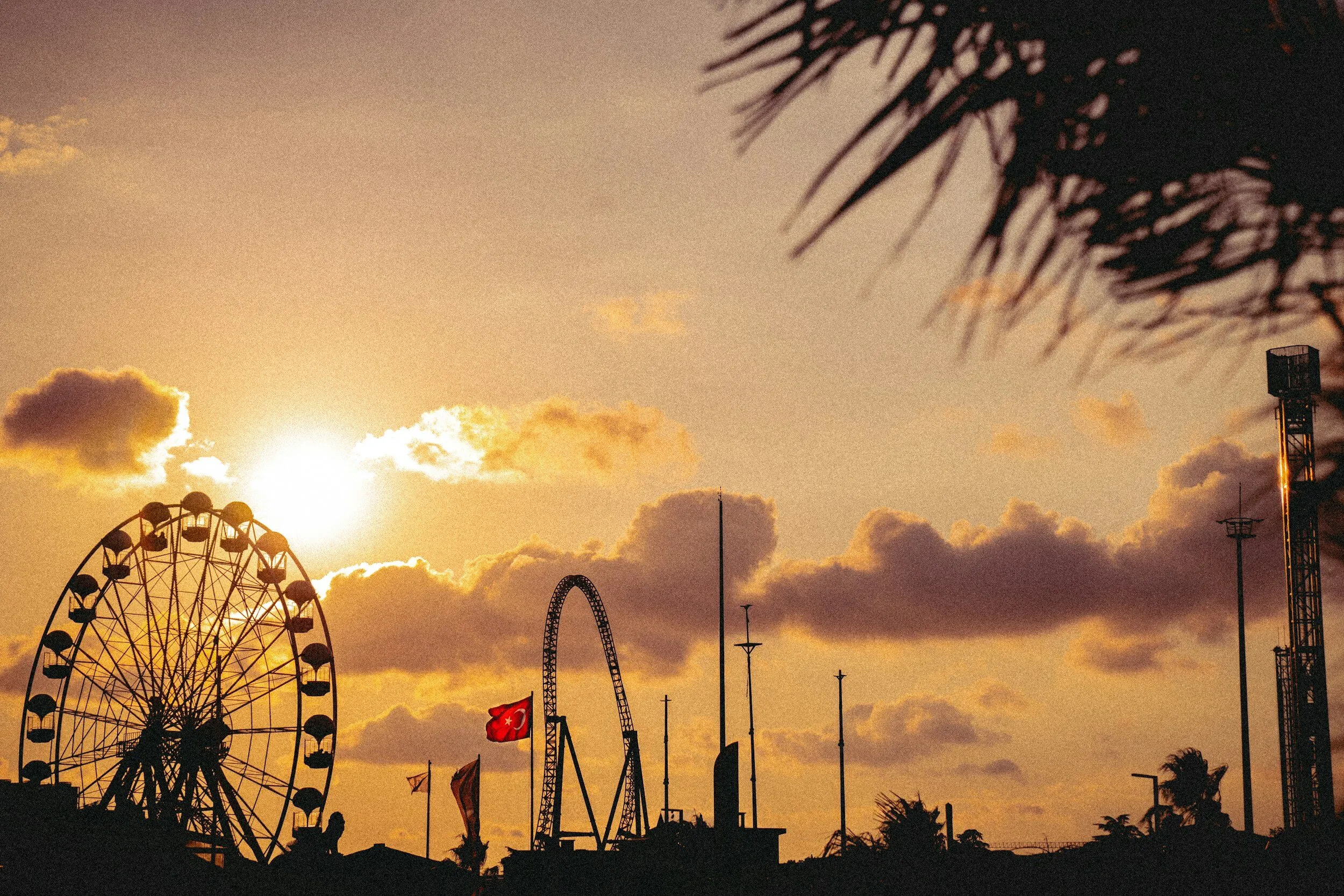 A ferris wheel sitting next to a ferris wheel under a cloudy sky.